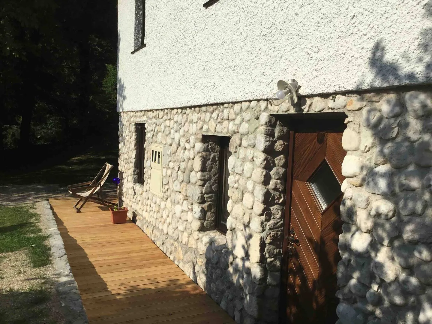 Kamniti zid hiše z lesenimi vrati spodnjega apartmaja